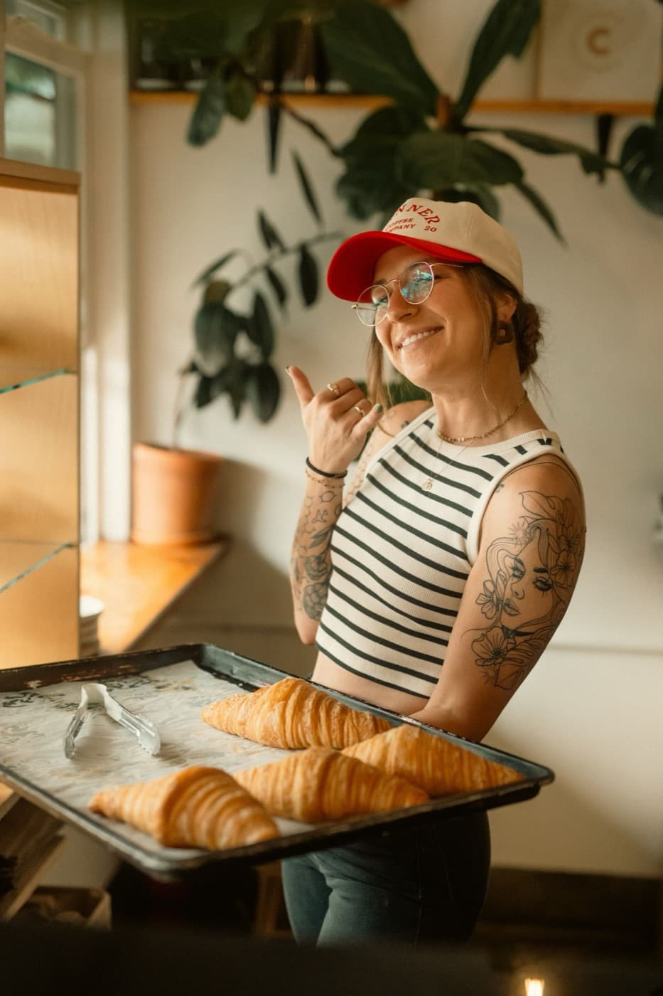Een bakker met een bakplaat croissants in haar zaak